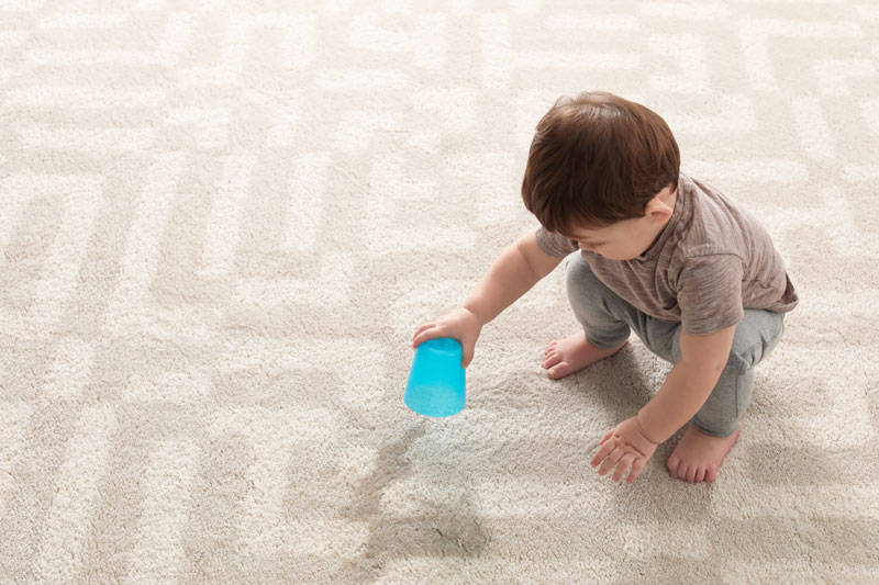 Young child spilling cup on carpet