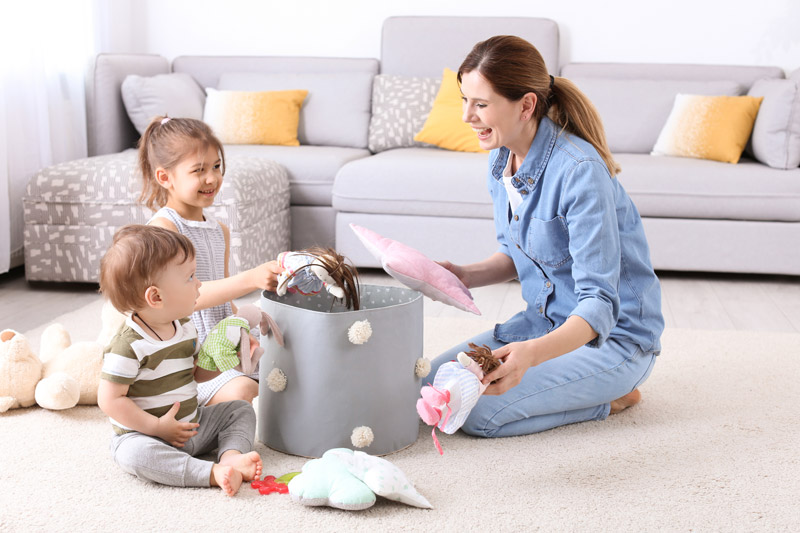 Mother and kids playing with plush toys on carpet