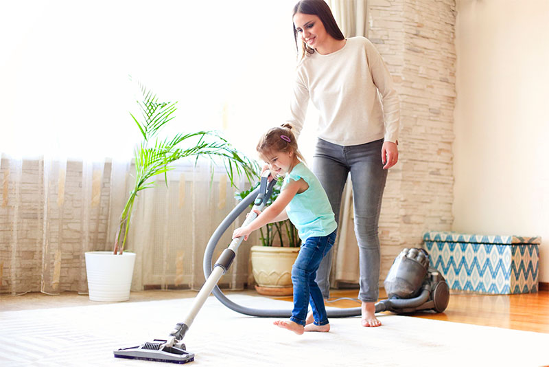 Mum and daughter vacuuming carpet