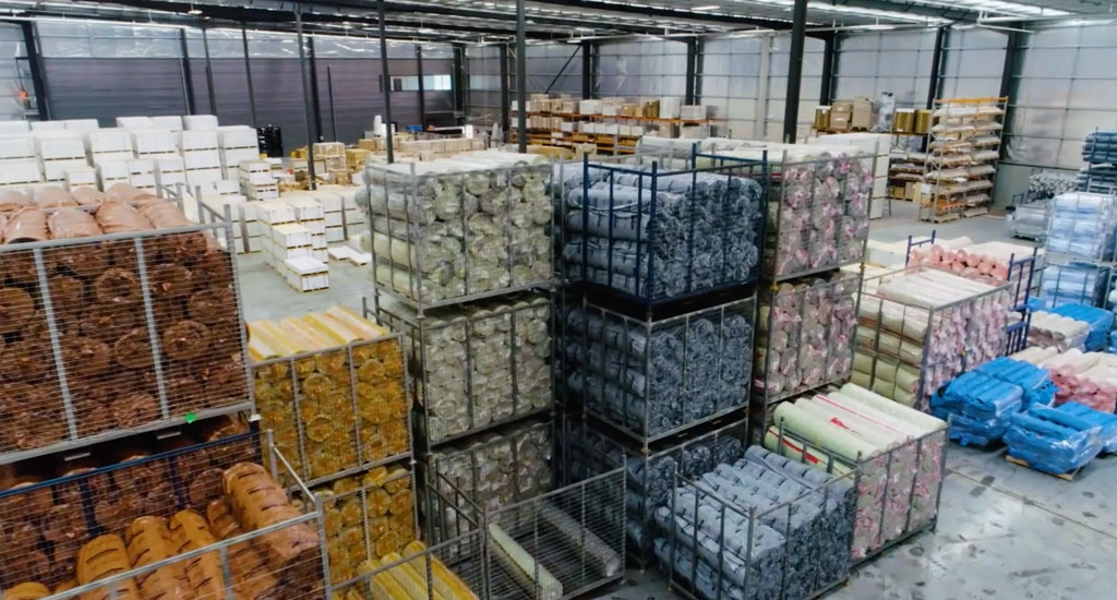 Rolls of underlay piled into metal crates in warehouse