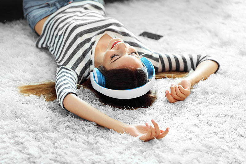 Woman lying on carpet while wearing headphones